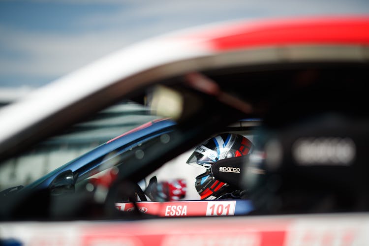 A Driver Wearing A Helmet Inside A Car