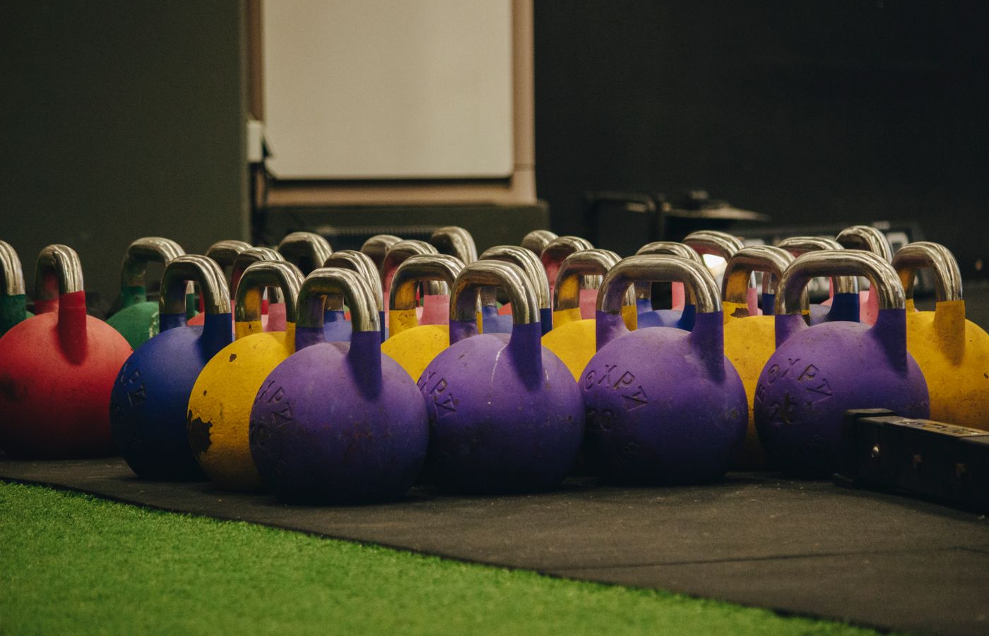 Vibrant kettlebells neatly arranged on the gym floor, ready for workout sessions.