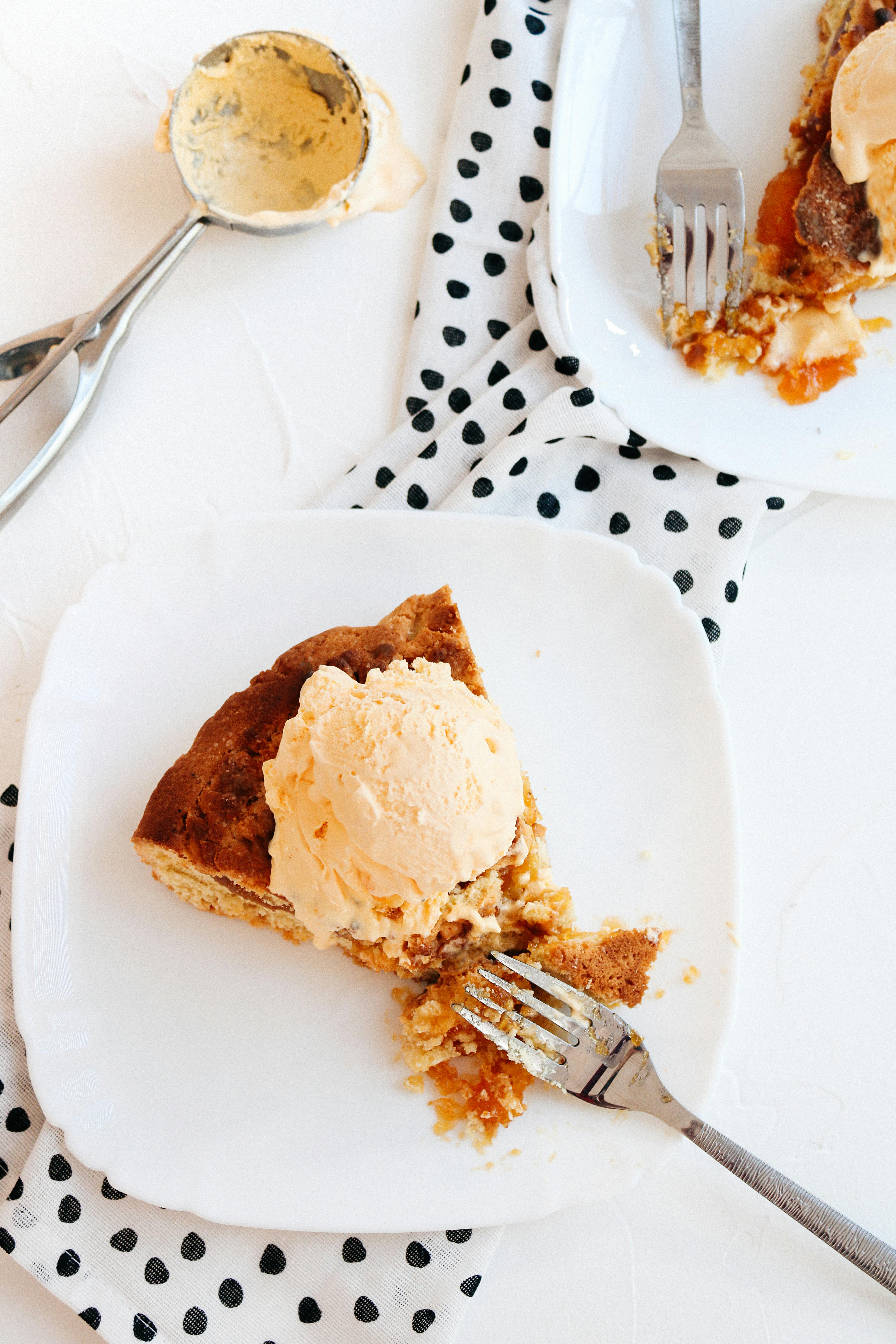 Delicious pumpkin pie topped with ice cream served on a ceramic plate. Perfect dessert scene.