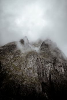 Majestic rocky mountain peaks shrouded in dense fog, creating a mysterious atmosphere.