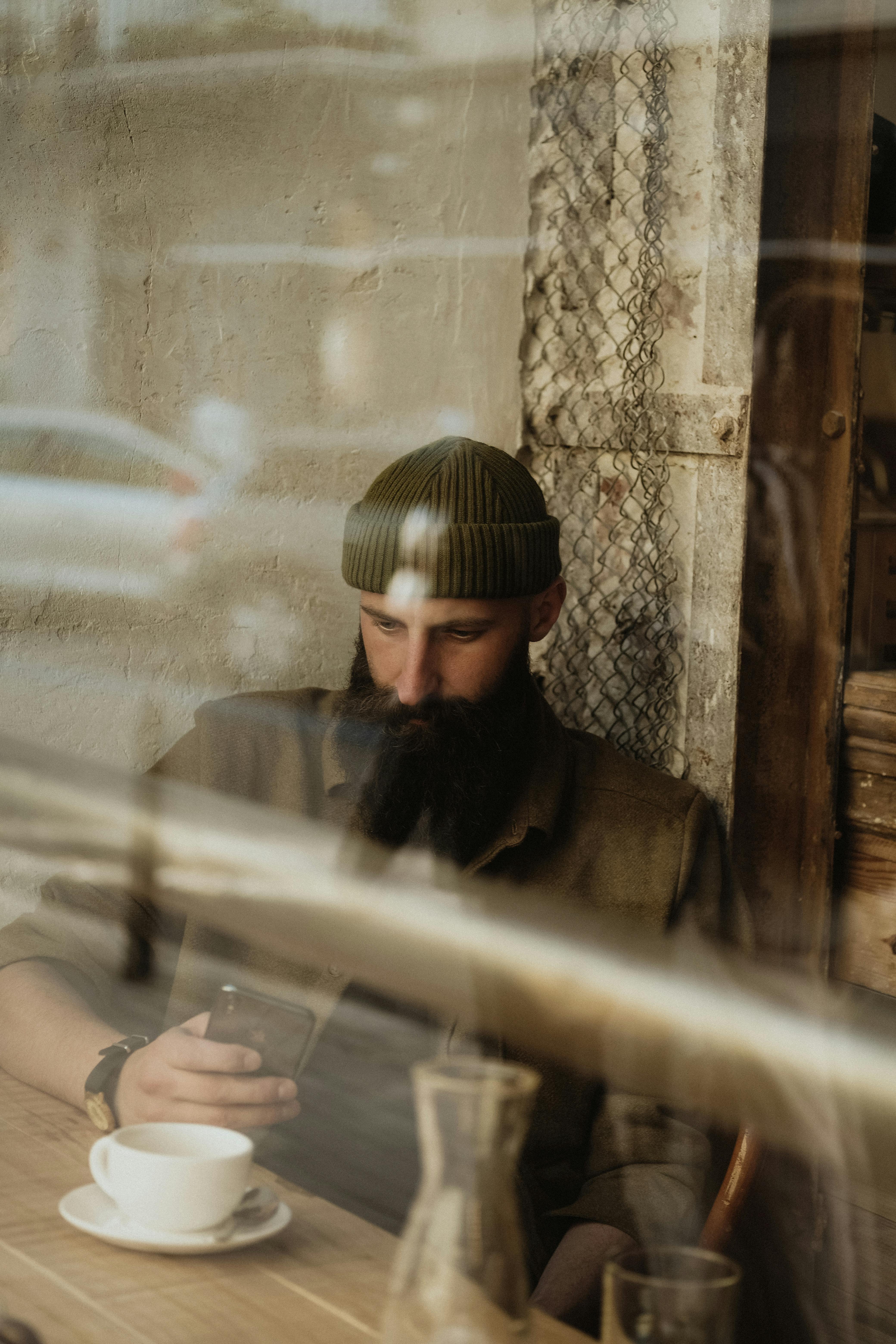 focused bearded man sitting at table in cafe