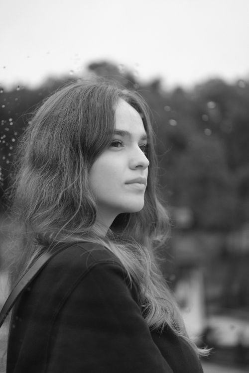 Free Black and white side view of young dreamy female with long wavy hair reflected in mirror outside Stock Photo