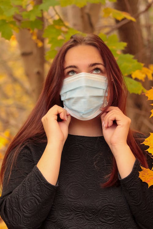 Free A Woman Looking Up while Wearing Face Mask Stock Photo