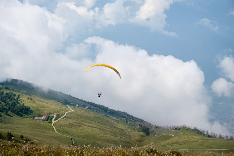 Person Paragliding Under Cloudy Sky