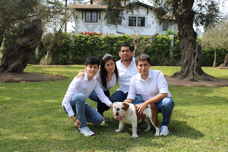 A Happy Family In White Clothes And Denim Jeans With Their Dog