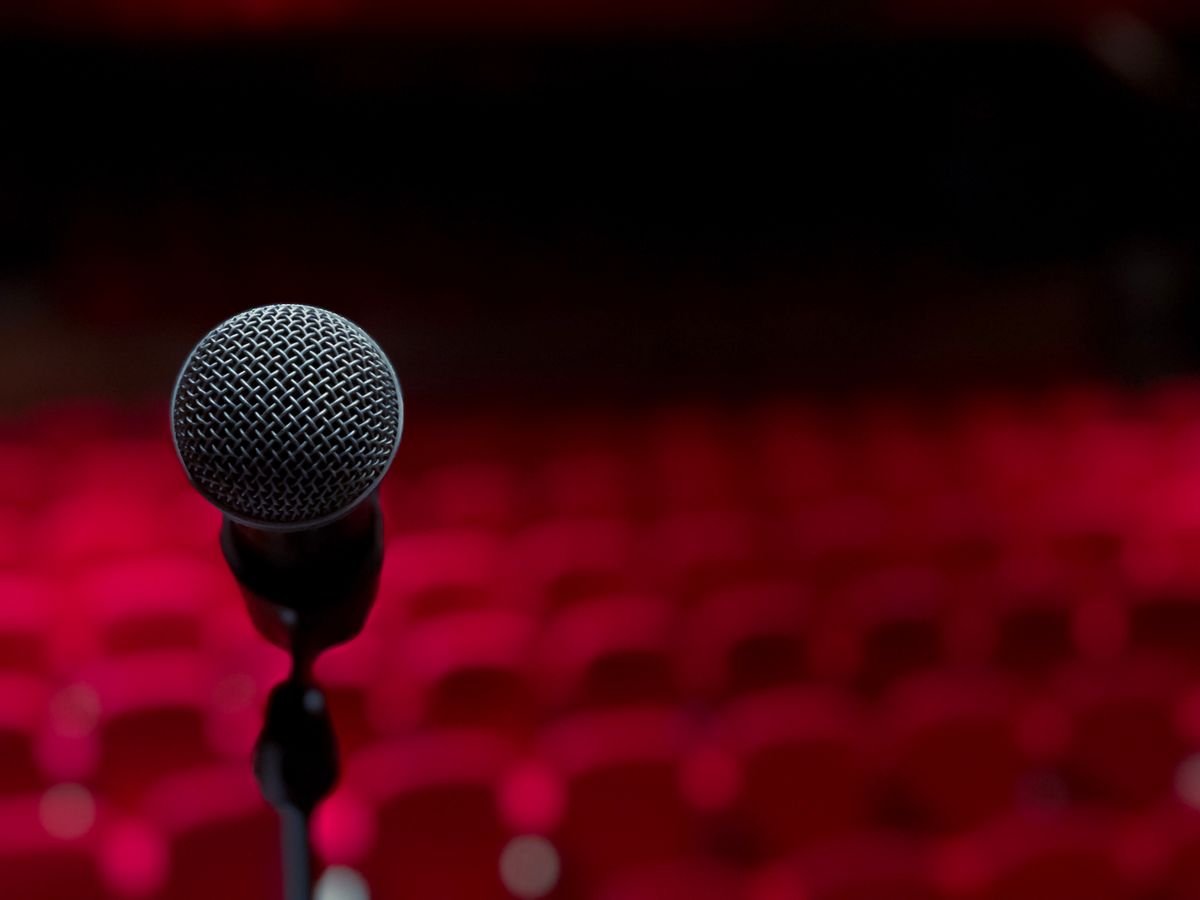 Microphone on a stage in front of empty red theater seats