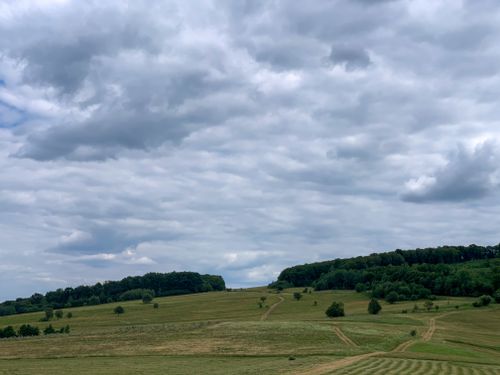 Free Picturesque rural landscape with grassy fields and a cloudy sky. Stock Photo