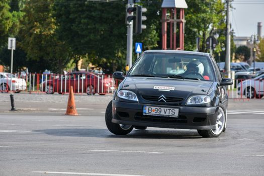 Black Citroen car takes a sharp turn during a street race in an urban setting.