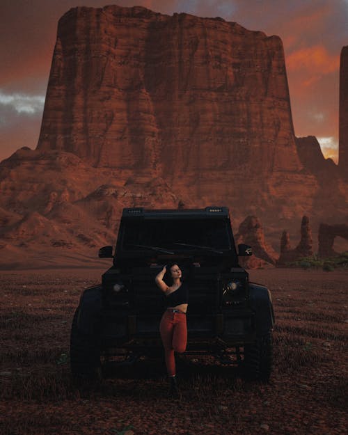Free A Woman Standing Near the Black Car Parked on the Desert Stock Photo