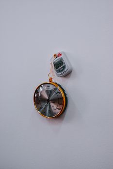 Photo showcasing analog and digital thermometers hanging on a white wall.