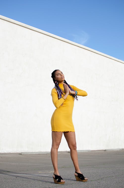 A Woman in Yellow Dress Standing with Her Hands Together