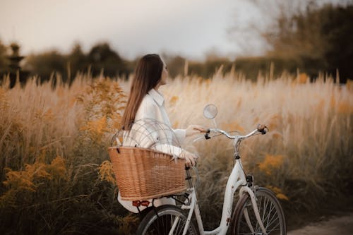 Free Woman in White Long Sleeve Shirt Standing Beside White Bicycle Stock Photo