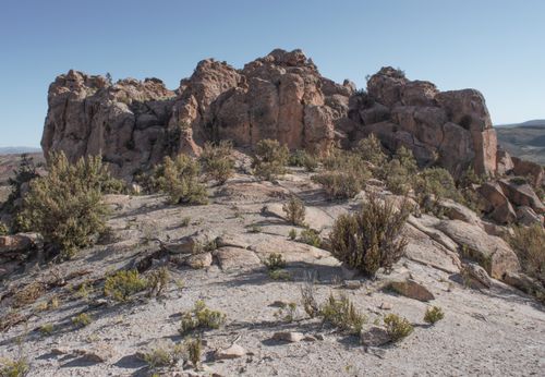 Free Explore rugged rock formations and sparse vegetation in a serene desert landscape. Stock Photo