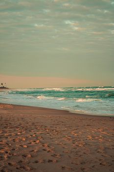 Peaceful shoreline view with gentle waves and soft sky lighting during dawn, offering a serene escape.
