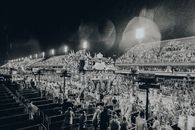 Black and white image of a vibrant parade at the Rio Carnival in the Sambadrome amidst rain.