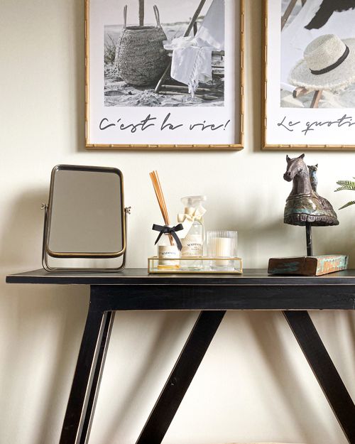 Free Elegant home interior featuring framed art, mirror, and stylish table décor. Stock Photo