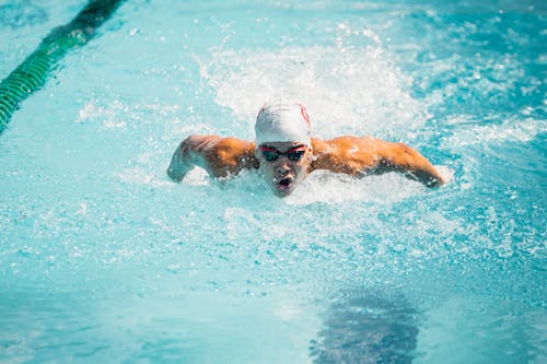 A Man Wearing Goggles and Swim Cap while Swimming