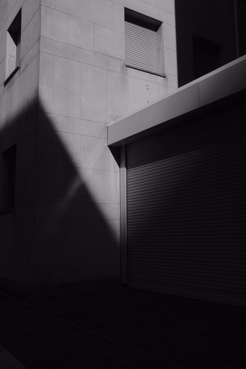 Free Shadow play on a modern building exterior with a roll-up door, showcasing architectural lines and contrasts. Stock Photo