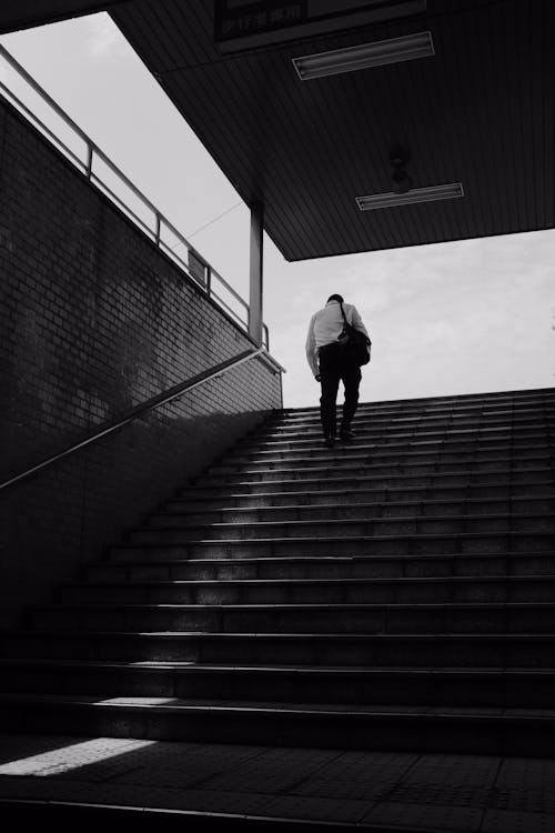 A Grayscale Photo of a Person Walking on Stairs