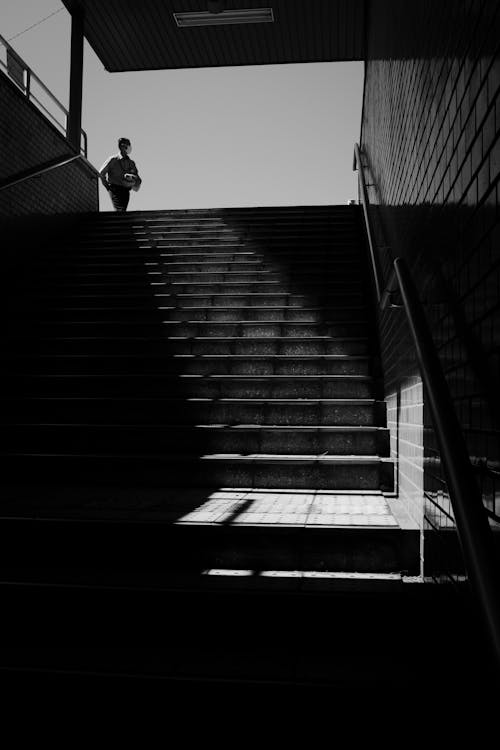 Grayscale Photo of Man Walking on Stairs