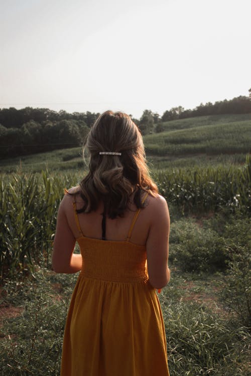 Free Woman in Yellow Spaghetti Strap Dress Standing on Grass Field Stock Photo