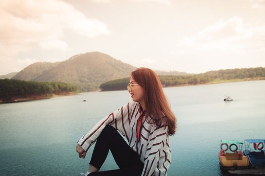 在越南大叻，一位穿着时尚的妇女正欣赏着群山环绕的宁静湖景