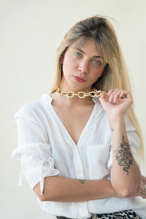 Woman in White Long Sleeves Wearing Gold Chain Necklace