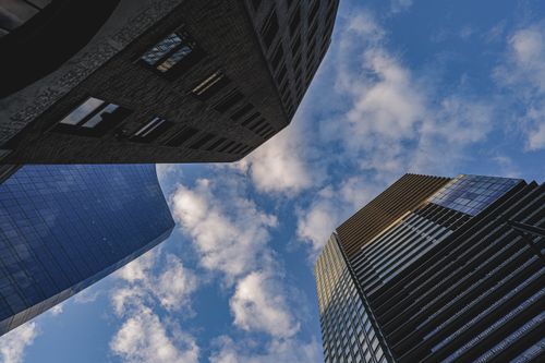 Free A low angle shot of modern skyscrapers against a blue sky with clouds. Stock Photo