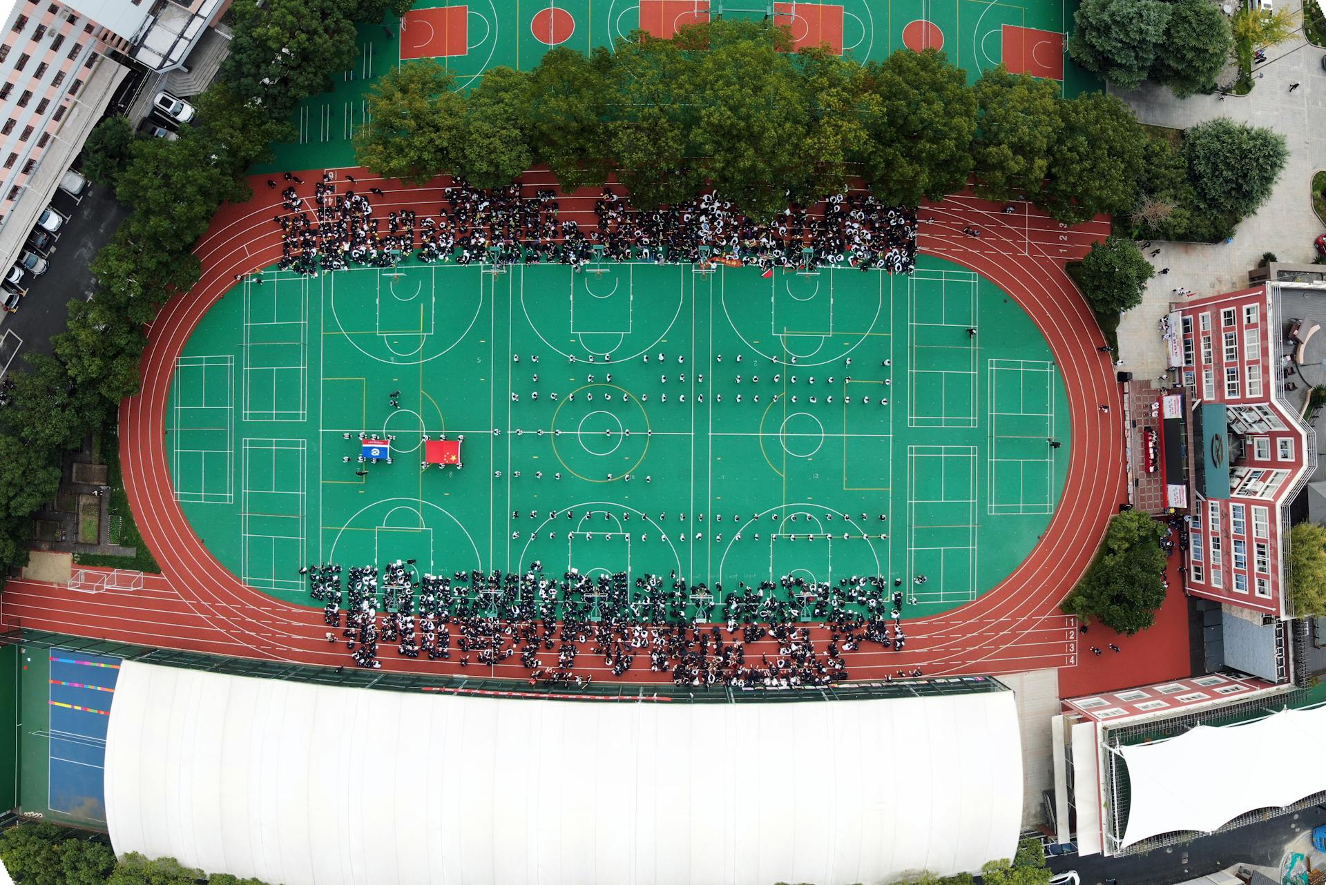 Aerial view of a sports complex in Shanghai with people gathered on a green field.