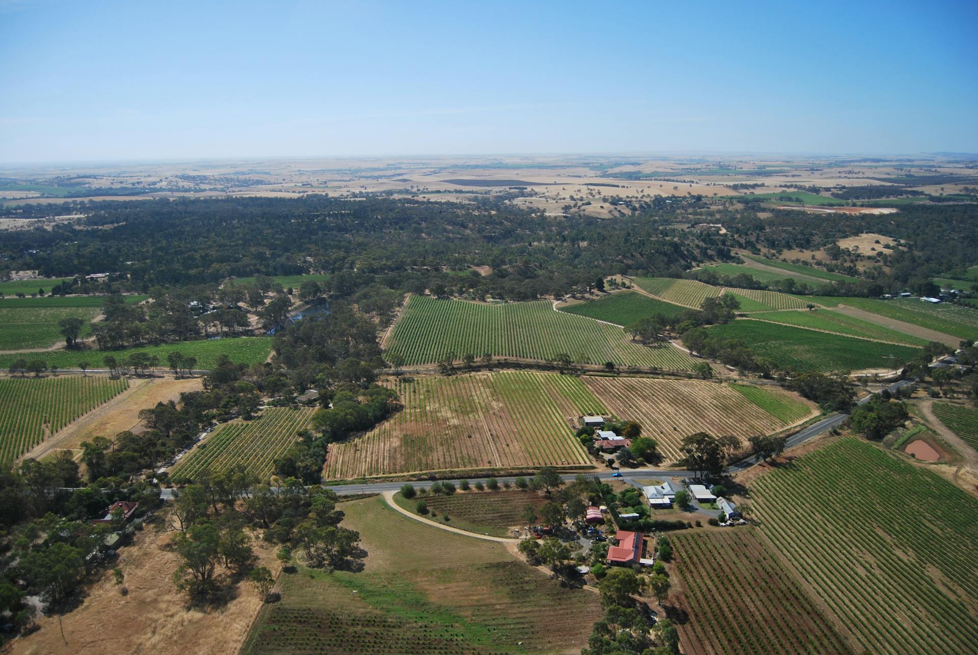 Aerial photograph showcasing vast rural agricultural lands and fields under a clear blue sky.