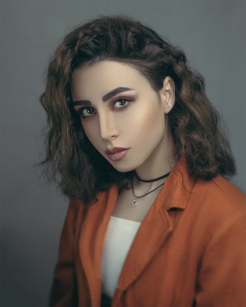 Free Studio portrait of a woman wearing an orange blazer and choker with stylish makeup. Stock Photo