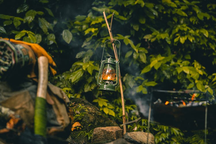 A Lighted Kerosene Lamp Hanging On A Stick On Rocks