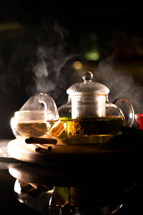 Free Elegant glass teapot and cup with steaming green tea and cinnamon sticks on a wooden tray. Stock Photo