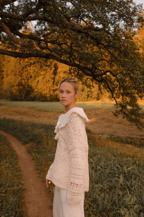 A Girl in Knitted Sweater Walking in an Unpaved Walkway
