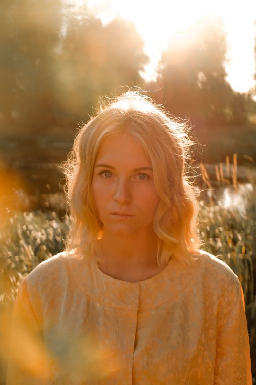 Free Portrait of a woman in a sunlit meadow with serene expression and blonde hair. Stock Photo