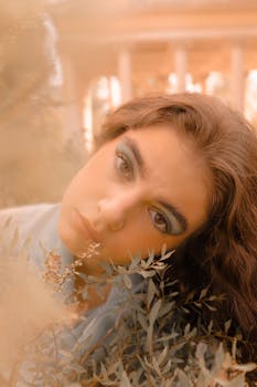 Beautiful close-up portrait of woman with natural makeup and leaves in soft, warm light.