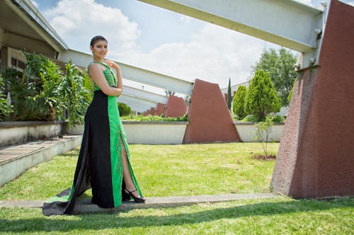 Woman in Green and Black Dress Standing in Front of Wall