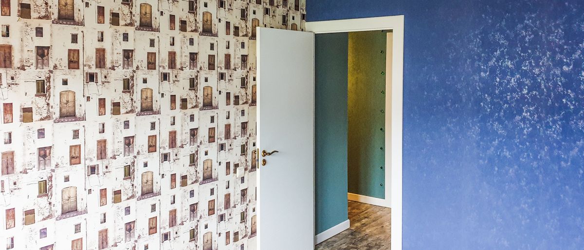 Old wallpaper being peeled and stripped off a wall