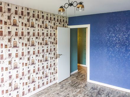 Wallpaper being stripped from a wall down to the drywall
