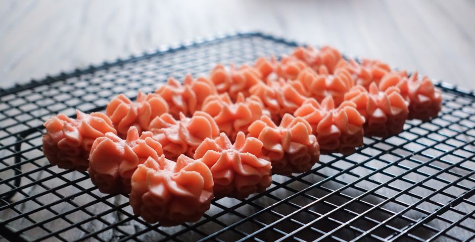 Delicious pink cookies decorated with frosting on a wire rack, perfect for desserts.