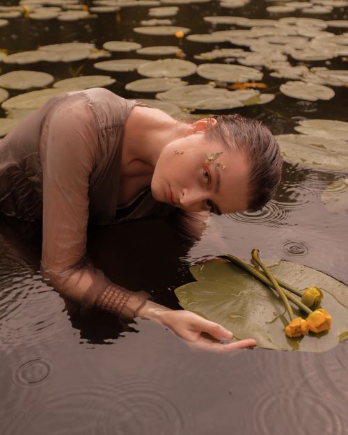Free Artistic portrait of a woman in water surrounded by lily pads, evoking a serene and dreamlike mood. Stock Photo