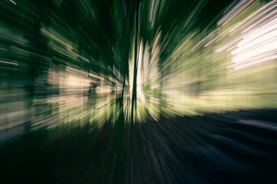 Abstract forest scene with motion blur effect, creating dynamic light streaks.