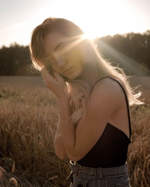 Free A serene portrait of a woman in a sunlit field capturing a peaceful summer moment. Stock Photo
