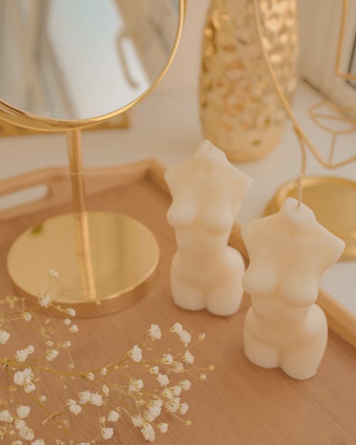 A Pair of Body Shaped Candles on a Wooden Tray with Flowers and Mirror