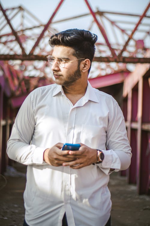 Free A Man in White Long Sleeves Holding His Phone Stock Photo