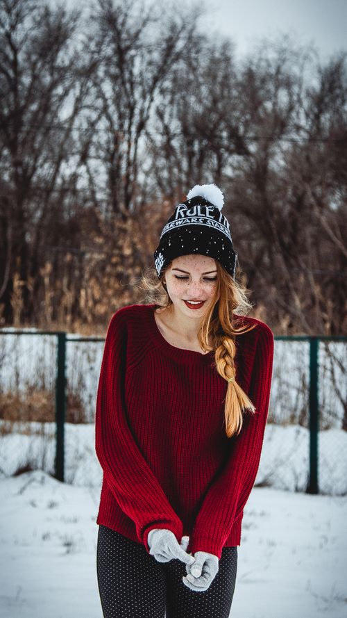 Free Young woman in a red sweater and beanie enjoying winter outdoors. Snowy setting in Russia. Stock Photo