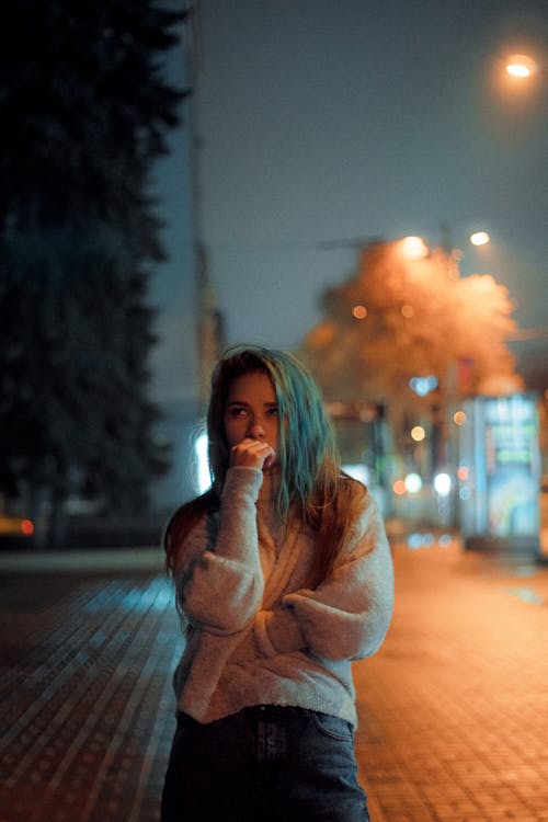 Free A Woman Standing on the Street at Night Stock Photo