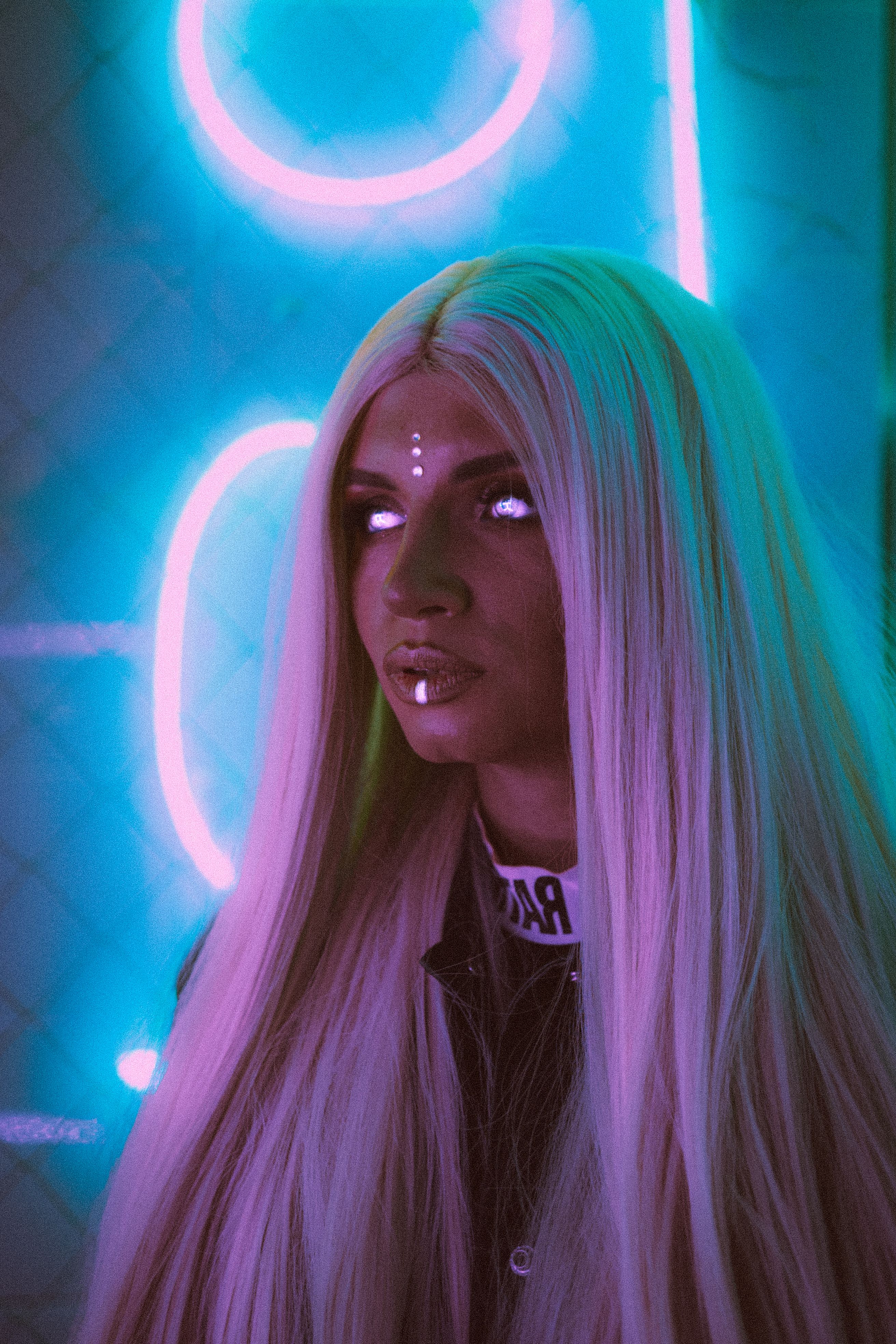 Striking portrait of a woman in cosplay with long blonde hair illuminated by neon lights for a modern, artistic flair.