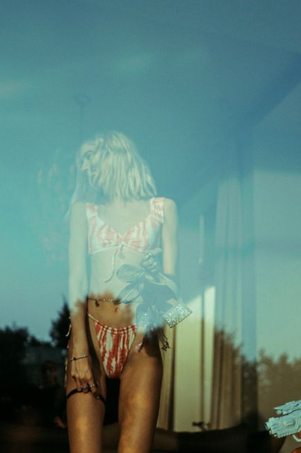 A creative shot of a woman in swimwear reflected in a glass window, creating a dreamy effect.
