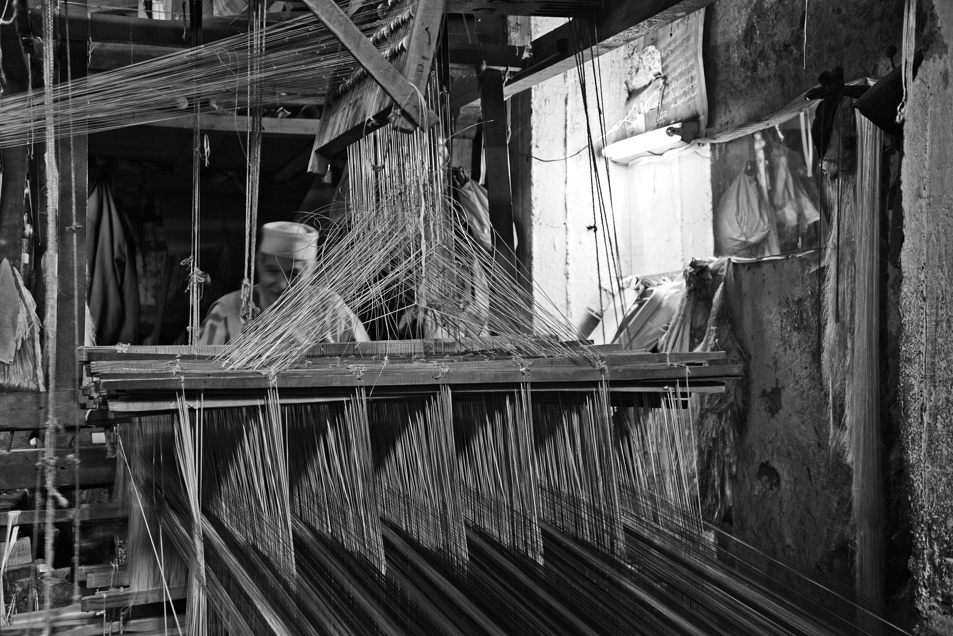 Black and white image of a traditional weaving workshop in Fes, Morocco showcasing artisan craftsmanship.